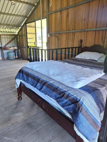 a bed in a room with a wooden floor at Cabaña Cherenga in Sarchí