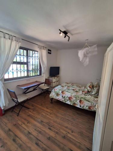 a bedroom with a bed and a desk and window at Adventure Cape Town 1 in Cape Town