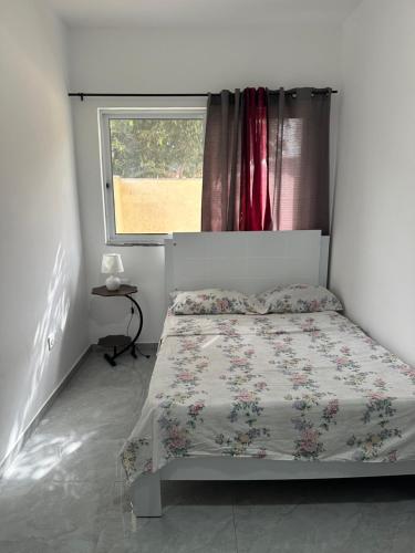 a bed in a bedroom with a window and a bedspread at Quarto- Espaço Casa Mendes in Praia