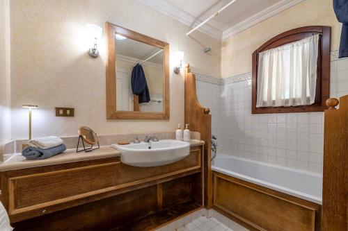 a bathroom with a sink and a tub and a mirror at Villa Belvedere Saline - Private Pool in Stintino