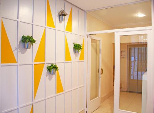 un pasillo con paredes amarillas y blancas con macetas en Roomin Hostel, en Salamanca