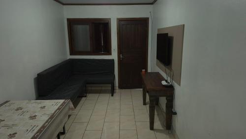 a living room with a couch and a television at Pousada Ventos Bons in Osório