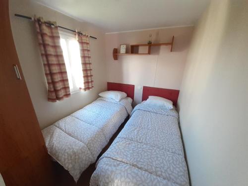 two beds in a small room with a window at Le doux refuge de l'Yères in Touffreville-sur-Eu