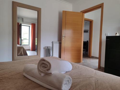 a bedroom with a bed with a towel on it and a mirror at Quinta dos Carvalhais - Serra da Estrela in Fornos de Algodres