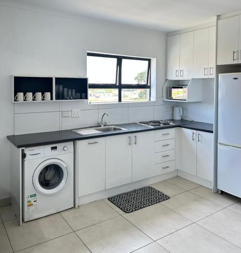 a white kitchen with a washing machine and a sink at Shine house in Somerset West