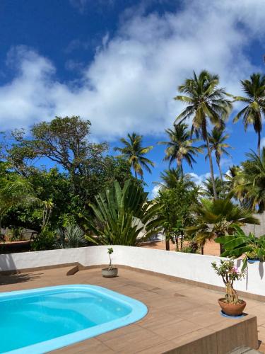 a swimming pool with palm trees in the background at Aconchego&Lazer in Piaçabuçu