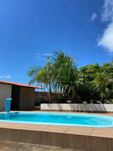 a swimming pool in front of a house with palm trees at Aconchego&Lazer in Piaçabuçu