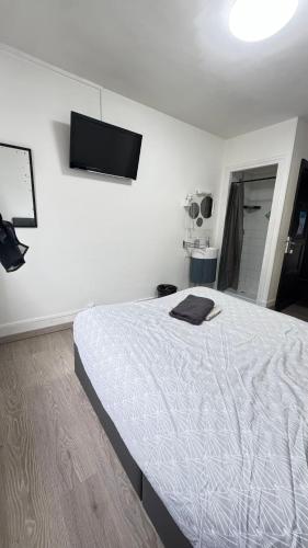 a bedroom with a white bed and a flat screen tv at Chambre 1 in Beauvais