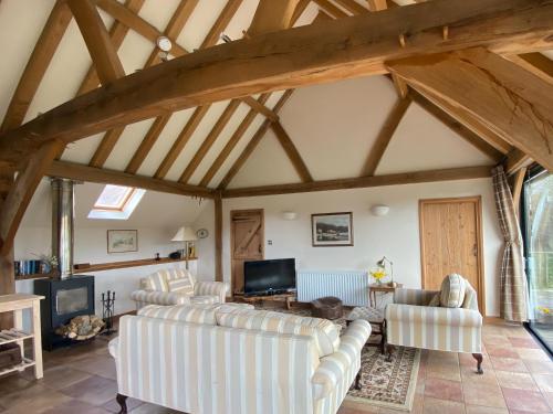 a living room with white furniture and wooden ceilings at The Old Carthouse in Steyning