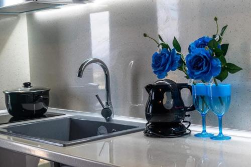 eine Küchentheke mit Spüle, blauen Gläsern und Blumen in der Unterkunft Blue line in Kalathos