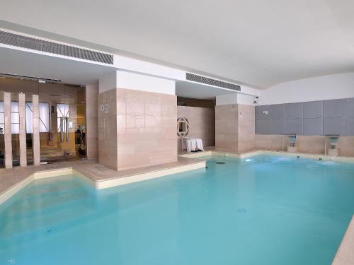 une grande piscine bleue dans un bâtiment dans l'établissement Sangallo Palace, à Pérouse