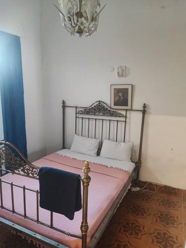 a bedroom with a bed with pink sheets and a chandelier at Historical House in Alsancak in Konak