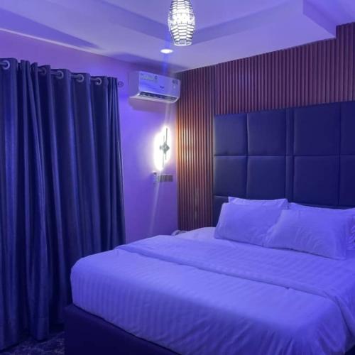a bedroom with a large white bed with purple lighting at Transvent Hotel And Suites in Abeokuta