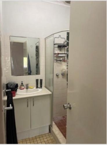 a bathroom with a sink and a shower with a mirror at Pearlers Lodge in Broome