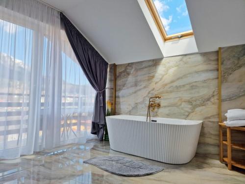 a bathroom with a tub and a large window at Casa Anitta in Buşteni