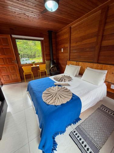 a bedroom with a large bed with a blue blanket at Refúgio Allamanda in Visconde De Maua