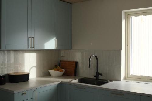 a kitchen with white cabinets and a sink and a window at Seaview Country House in Pettvik