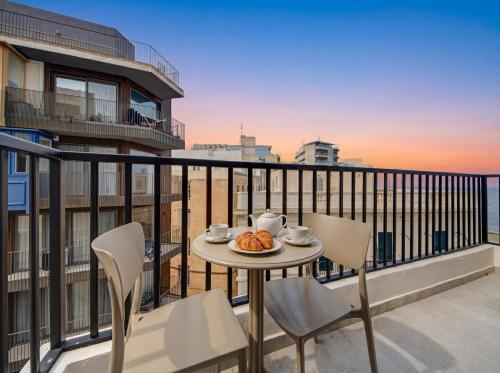 a table with a plate of food on a balcony at Sliema Seaview 4BD Apartments & Penthouse with Jacuzzi in Sliema
