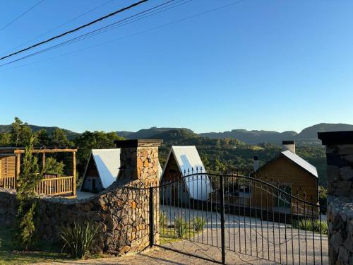 a fence in front of a house with mountains in the background at Reserva Linha Bonita - Chalés Românticos in Gramado