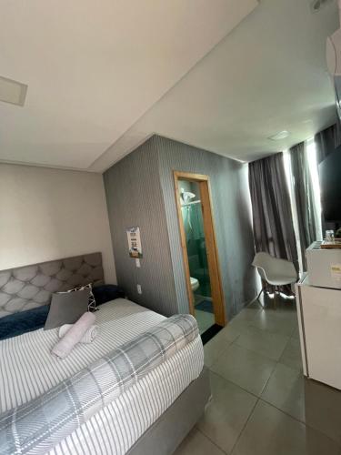 a bedroom with a bed and a table and a chair at Studio compacto em Camboriú in Camboriú