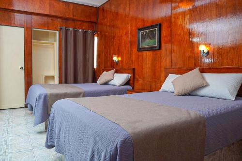 two beds in a room with wooden walls at Hotel GranMadero in Durango