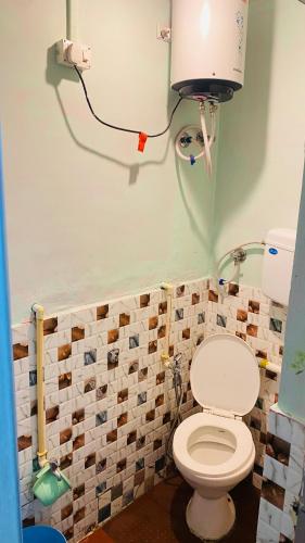 a bathroom with a toilet and a light on the wall at Arbuda inn in Mount Ābu
