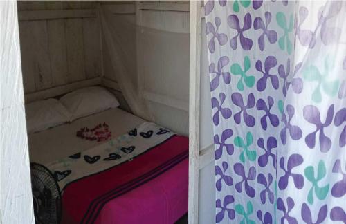 a small bed in a small room with a curtain at Cabaña Luna Nueva in Buenaventura