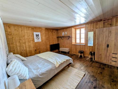 a bedroom with a bed in a room with wooden walls at Le refuge de Marius - logement de colpoteur in Albiez-Montrond