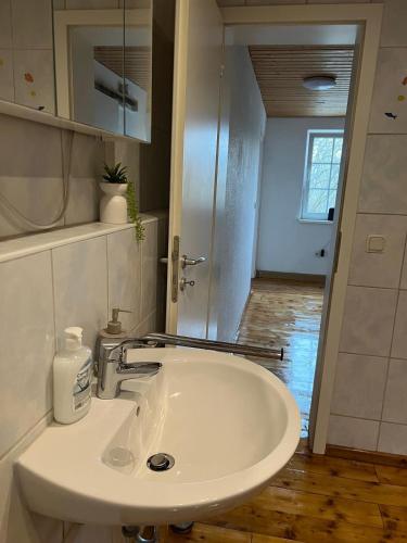 a white sink in a bathroom with a hallway at Mehrere Zimmer in erster Lage in Siegen