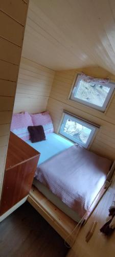 two beds in a small room with two windows at Tiny house Horní Planá in Horní Planá