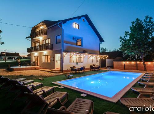 a house with a swimming pool in front of a house at Apartments Villa Mavi Plitvice in Drežnik Grad