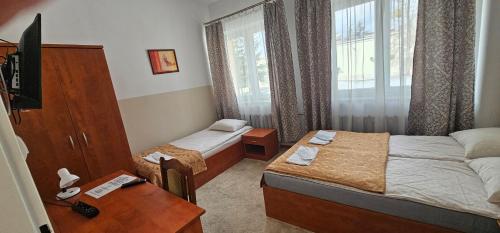 ein Hotelzimmer mit zwei Betten, einem Tisch und einem Schreibtisch in der Unterkunft Rest Hostel Airport Modlin in Nowy Dwór Mazowiecki