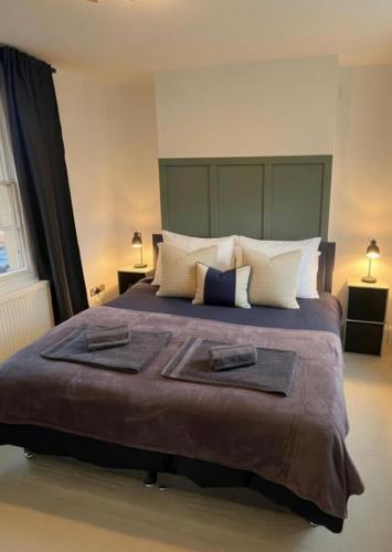 a bedroom with a large bed with two towels on it at Cosy Townhouse in Central Leamington with parking in Leamington Spa