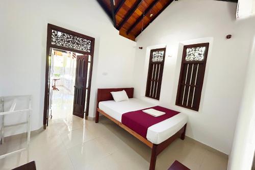 a bedroom with a bed and two windows in it at Ilamperuma Bungalow in Weligama