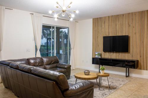 a living room with a leather couch and a flat screen tv at 6 Bedrooms 5.5 Bathrooms Solterra 4193 OD in Orlando