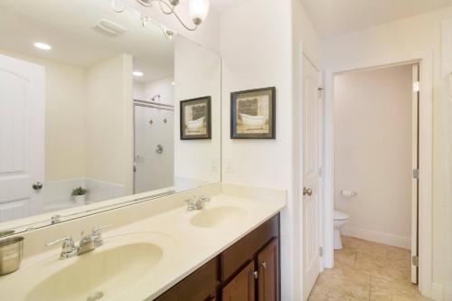 a bathroom with two sinks and a mirror at 6 Bedrooms 5.5 Bathrooms Solterra 4193 OD in Orlando