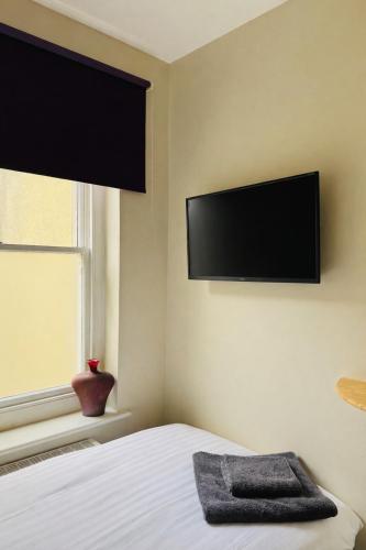 a bedroom with a bed with a flat screen tv on the wall at Bed for the night, Close to Beach, Shops , Train in St. Leonards