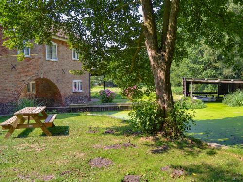 a picnic table and a tree in front of a building at The Wherry Arch in Neatishead