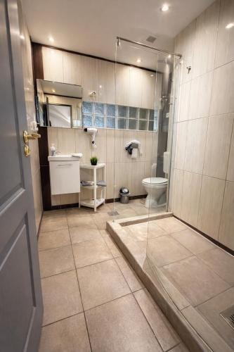 a bathroom with a glass shower and a toilet at Panzió Apartments in Budapest