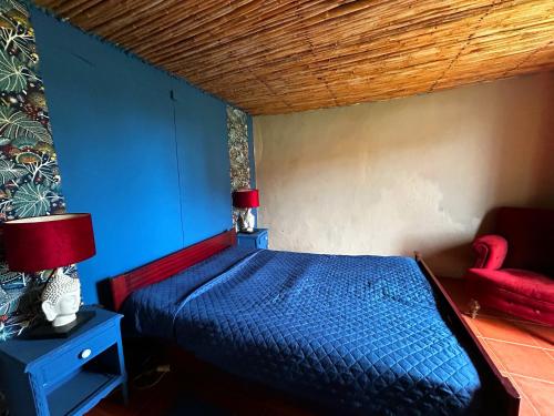 a bedroom with a blue bed and a red chair at The Cottage Guest House in Vale Coelho