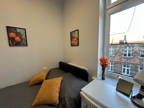 a bedroom with a bed and a desk and a window at MMRent Orange Room in Gdańsk
