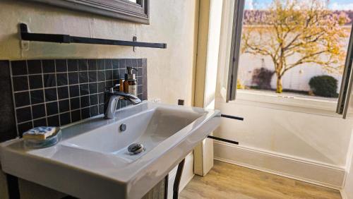 a white sink in a kitchen with a window at L'Aube du Lac in Drosnay