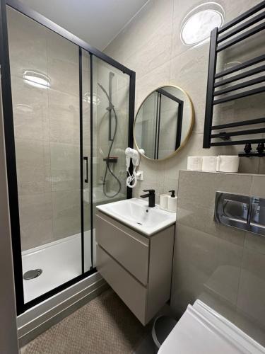 a bathroom with a shower and a sink and a mirror at MMRent Orange Room in Gdańsk