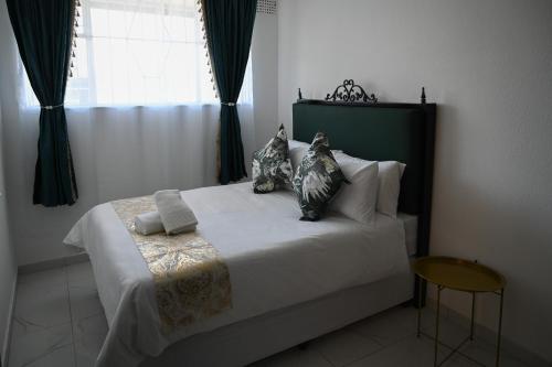 a bedroom with a white bed with pillows and a window at Lagrande CBD in Benoni