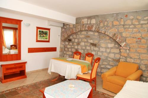 a room with a table and chairs and a stone wall at Apartments Residence Astoria in Rab