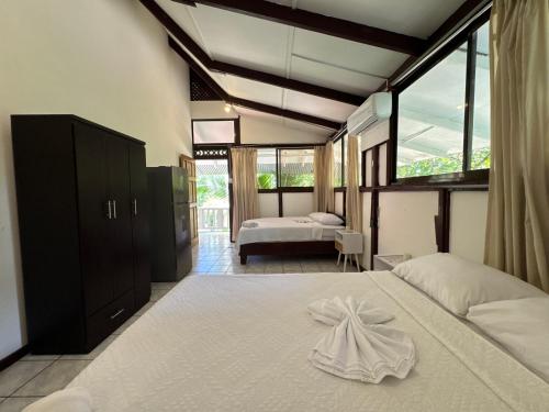 a bedroom with two beds and a large window at Arrecife Punta Uva - Hospedaje, bar y restaurante - Frente al mar in Punta Uva