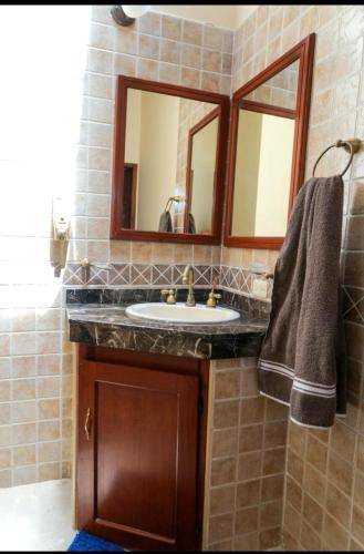 a bathroom with a sink and two mirrors at La Mona in Calima
