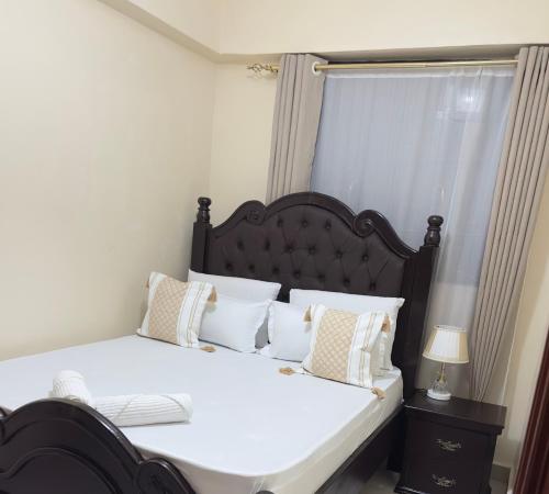 a bedroom with a large bed with white sheets and pillows at ZulynHomes in Kisumu