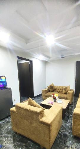 a living room with couches and a flat screen tv at Dawood Apartments Bahria Town Lahore in Lahore