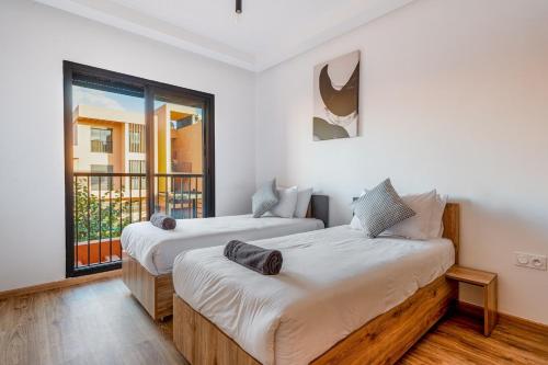 two beds in a room with a balcony at Noria Golf Apartment in Marrakesh